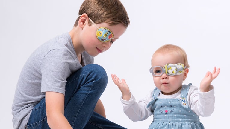Boy wearing a Kay Eye Patch and a baby wearing a Kay Fun Patch playing with toy blocks